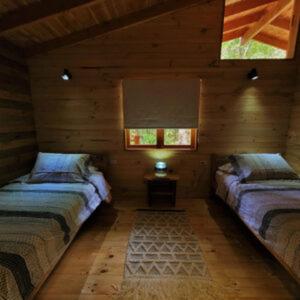 a room with two beds in a log cabin at Entre arrayanes lodge in Curarrehue