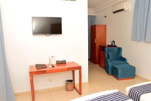ein Zimmer mit einem Tisch, einem Stuhl und einem Fernseher in der Unterkunft Le Feto 3 in Dakar