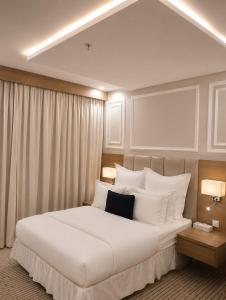 a bedroom with a large white bed with white pillows at فندق حي الربوه Al Rabwah District Hotel in Tabuk