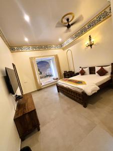 a bedroom with a bed and a television in it at Agastya Vilas Resort in Dhandni +14 photos