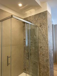 a glass shower in a bathroom with a stone wall at Villa Miranda RELAX in Ortona