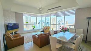 a living room with a table and chairs and a television at Luxury Skyline Apartment with Panoramic Views in Sharjah
