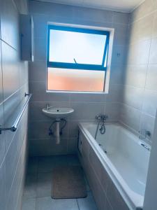 a bathroom with a sink and a tub and a window at Number 8 in Maseru