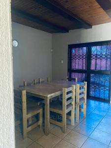 a wooden dining room table and chairs with stained glass windows at Number 8 in Maseru