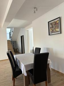 a dining room table with black chairs and a white table cloth at Pensiunea SAUVAGE in Corbu
