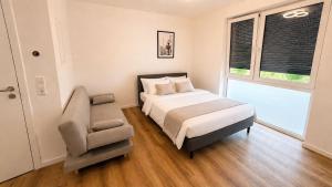 a bedroom with a bed and a chair and a window at StayIN Suites in Griesheim