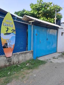 a blue building with a surfboard next to a fence at Hostal Niña Oly in El Sunzal