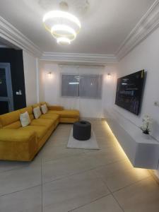 a living room with a yellow couch and a tv at Studio VIP - 01 chambre - Bonamoussadi groupe électrogène - 2douches in Douala