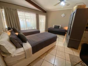 a bedroom with two beds and a flat screen tv at Slaapnet Guesthouse Long Stay Accommodation Wilkoppies in Klerksdorp