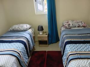 two beds in a room with blue curtains and a night stand at Sucasa Apartment B in Willemstad +7 photos