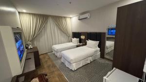 a hotel room with two beds and a flat screen tv at فندق حي الربوه Al Rabwah District Hotel in Tabuk