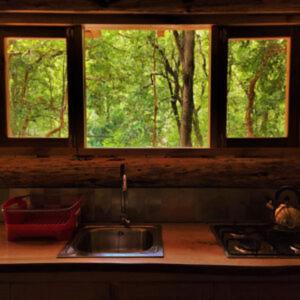 a kitchen counter with a sink and two windows at Entre arrayanes lodge in Curarrehue