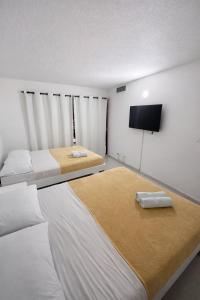 a bedroom with two beds and a flat screen tv at Al Reef Apartamentos TOP in San Andrés