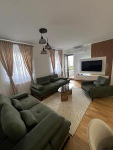 a living room with green couches and a flat screen tv at Apartman 15 in Novi Sad