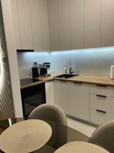 a kitchen with white cabinets and a table and chairs at Apartman 15 in Novi Sad
