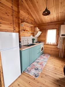 a kitchen with a white refrigerator in a wooden cabin at chemtan cottages in Dushetʼi