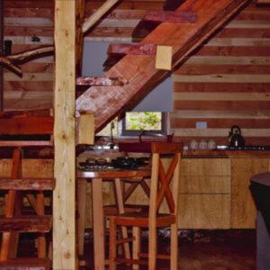 a kitchen with a table and chairs in a cabin at Entre arrayanes lodge in Curarrehue