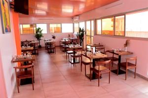 ein Restaurant mit Holztischen und -stühlen und Fenstern in der Unterkunft Le Feto 3 in Dakar