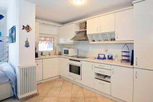 a kitchen with white cabinets and white appliances at FILIPPIDIS suites in Neos Marmaras
