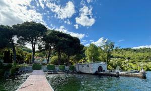 a bridge over a body of water with trees at Casa Blanca - Villa with pool and private beach in Lesa +32 photos