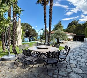 a patio with a table and chairs and a umbrella at Casa Blanca - Villa with pool and private beach in Lesa