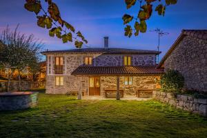 an exterior view of a stone house with a yard at CASA DAS XACIAS, RIBEIRA SACRA in A Airoa