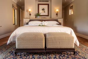 ein Schlafzimmer mit einem großen Bett und zwei Ottomanen in der Unterkunft Avianto in Muldersdrift