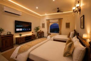 a bedroom with two beds and a flat screen tv at Agastya Vilas Resort in Dhandni