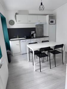a white kitchen with a white table and chairs at Petit cocon près des grottes de Perrier in Perrier