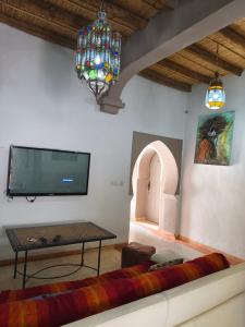 a living room with a couch and a tv on the wall at Hôte sahara & spa TADIGHOUST in El Hara