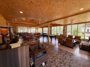 a large living room with tables and chairs and windows at Skywood by Vankuteer - Pool & Mountain view Rooms in Kandāghāt