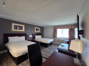 ein Hotelzimmer mit zwei Betten und einem Tisch in der Unterkunft Saffron Inn in Auburn