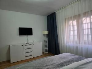a bedroom with a bed and a dresser with a television at Vila Adina in Eforie Nord
