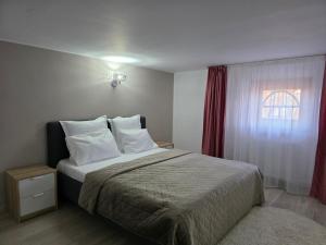 a bedroom with a bed with white pillows and a window at Vila Adina in Eforie Nord