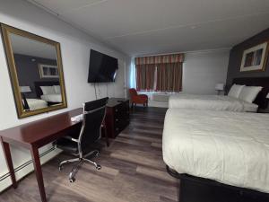 ein Hotelzimmer mit zwei Betten, einem Schreibtisch und einem Spiegel in der Unterkunft Saffron Inn in Auburn