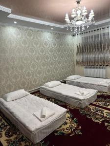 a room with three beds and a chandelier at Marjan Guest House in Bokonbayevo