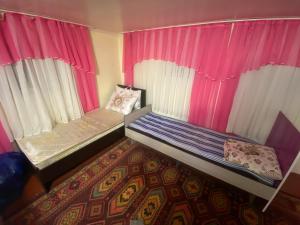 a small room with a bed and pink curtains at ILGIZ HOUSE Barskoon in Barskoon