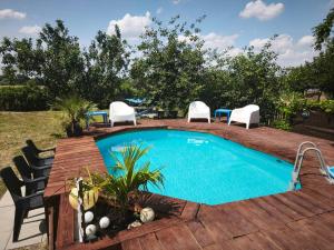 a swimming pool with a wooden deck and chairs next to it at Blanka Villa Wellness Home in Bakonyszentlászló
