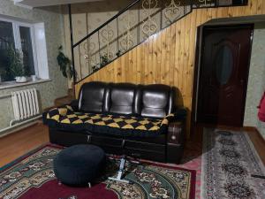 a black leather couch in a living room with a staircase at ILGIZ HOUSE Barskoon in Barskoon