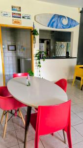 a white table and red chairs in a room at Casa Swell Hostel in Fernando de Noronha