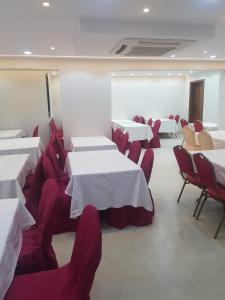 a dining room with white tables and red chairs at فندق الراية الماسية in Mecca