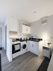 a kitchen with white cabinets and a washer and dryer at The Studio Room in Brentwood