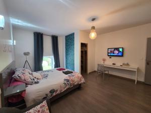 a bedroom with a bed and a desk and a television at Les étangs du moulin d'Harcy in Lonny
