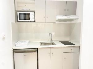a white kitchen with a sink and a microwave at Κωνσταντίνος Έλενα Studios in Pefki