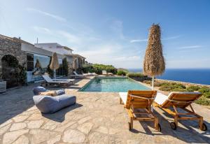 a villa with a swimming pool and two lawn chairs at Astarte Sifnos in Artemonas