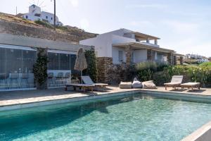 a swimming pool with chairs and a house at Astarte Sifnos in Artemonas