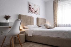 a bedroom with a bed and a white chair at Drava Osijek in Osijek