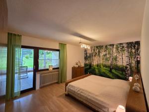 a bedroom with a bed and a mural of trees at Ferienwohnung Sonnenberg am Radweg in Gedern