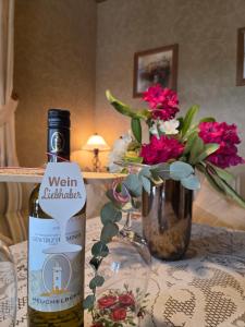 a bottle of wine and a vase of flowers on a table at Ferienwohnung Sonnenberg am Radweg in Gedern