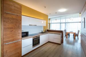 a kitchen with white cabinets and a table with chairs at TATRYSTAY Private Apartments Hrebienok in Starý Smokovec